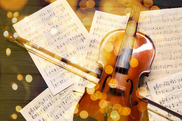 Christmas and New Year music. Violin and music sheets on wooden background, bokeh effect © New Africa