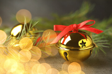 Christmas music. Jingle bells and fir tree branch on grey table, bokeh effect