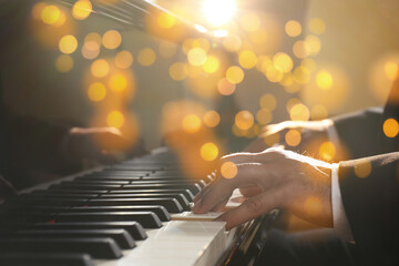 Christmas and New Year music. Man playing piano, closeup. Bokeh effect