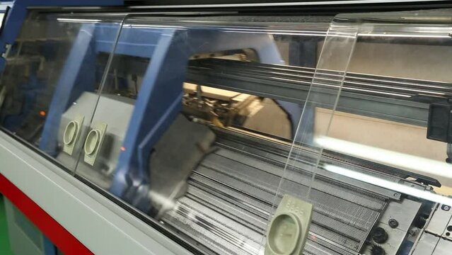 View of working knitting machine in workshop. A row of industrial textil flat knitting machines in a knitwear factory. Manufacture of knitwear, modern computerized flat Knitting Machine
