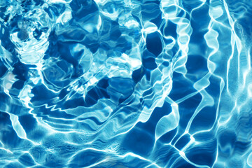 Waves on dark blue water in sunlight. Pool, river, ocean. Blue textured background for your design. Selective focus, defocus