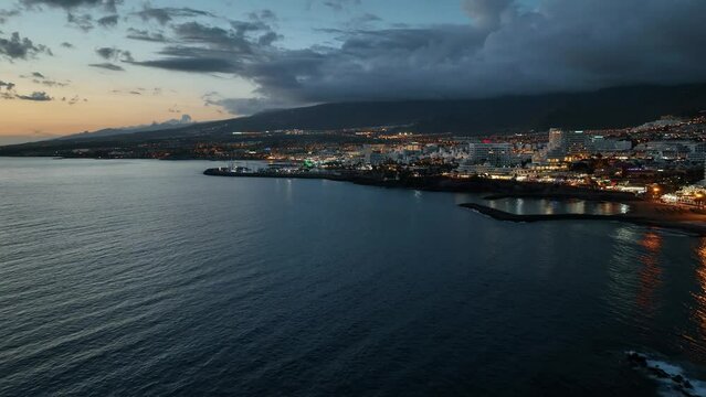 Veduta dal mare della costa di Tenerife al crepuscolo, nubi nel cielo e luci sulla citt&agrave;: Parte 1