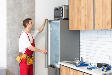 Worker repairing fridge in kitchen