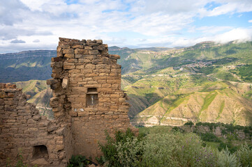 Fototapeta na wymiar Landscape of the old ruins of an ancient city in an abandoned mountain village, located on a steep hillside among a mountainous landscape. Gamsutl, Dagestan, Russia.
