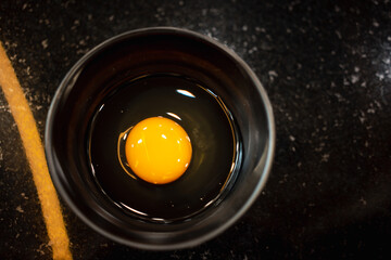 Bowl of egg yolk on black bowl from above