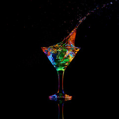 Ice cube falling down into glass with martini cocktail against dark background with neon light. Traditional taste. Concept of alcohol drink, nightclub, party, taste, celebration.
