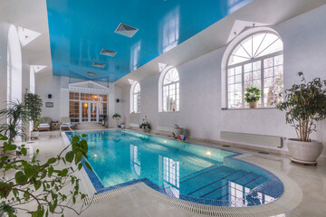 A swimming pool with convenient steps for descent in the interior of a luxurious mansion....