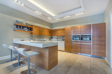 Modern kitchen interior design. Kitchen set made of dark wood with white countertops. .Grey bar...