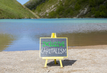 Inclusive capitalism symbol. Concept words Inclusive capitalism on beautiful black chalk blackboard. Beautiful sand beach mountain lake background. Business inclusive capitalism concept. Copy space.