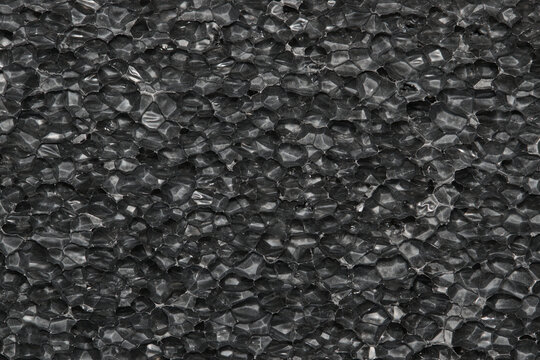 Black Expanded polyethylene foam sample background. EPE beads packing material with macro detail cells, textures and one solid color.
