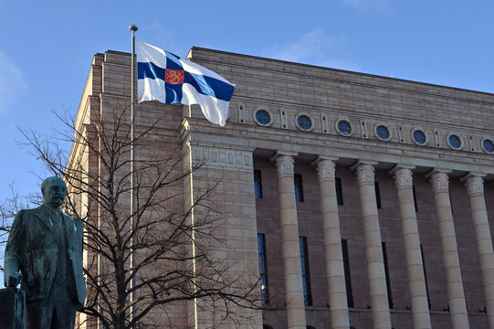 the monument to third president of Finland Pehr Evind Svinhufvud, waving Finnish flag and Finnish parliament building, December 6, 2023