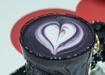 filiżanka fioletowej kawy z dekoracyjnym sercem z bitej śmietany.