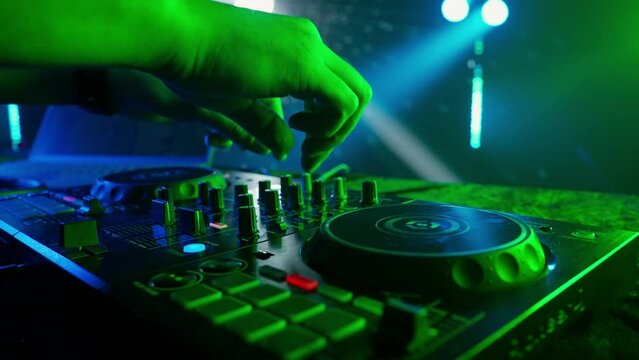 DJ's Hands Adjusting Sound Mixer Under Club Lights