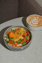 Healthy breakfast. Oat porridge, muesli with mango, honey in a ceramic bowl with a cup of latte coffee. Served on table in restaurant, cafe. Morning breakfast concept, banner. Diet Nutrition Concept