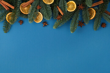 Christmas blue background with fir tree, dried orange, cinnamons and star anise. Top view with copy space for your text