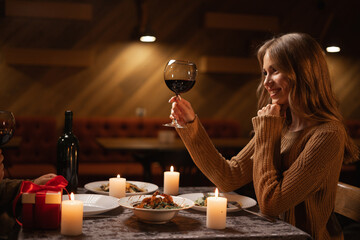 Romantic date, Valentine's day celebration, young couple clinking glasses of wine in a restaurant...