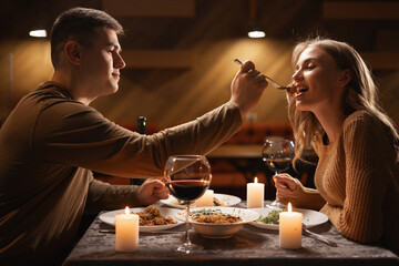 Romantic Relationship. Couple in love have dinner in cafe. Smiling man is feeding his woman....