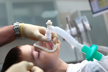 A child with an oxygen mask on his face. Preparing the child for anesthesia. Dental surgery under...