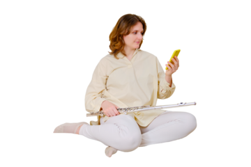 Happy woman musician with flute looking at mobile phone at home on sofa in living room, isolated on a white background