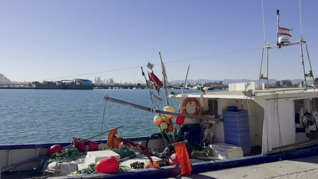 Fishing boats and ships in the port of Castellon in winter. Port cranes on the horizon. Red floats for nets. Port of El Grao. Spain
