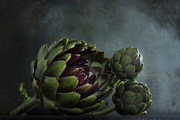 Obraz premium Fresh green artichoke on a blurred background. Artichokes on a dark background. Copy space.
