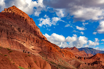 Wall of an arid and rugged hill with great erosion and a sky with clouds.