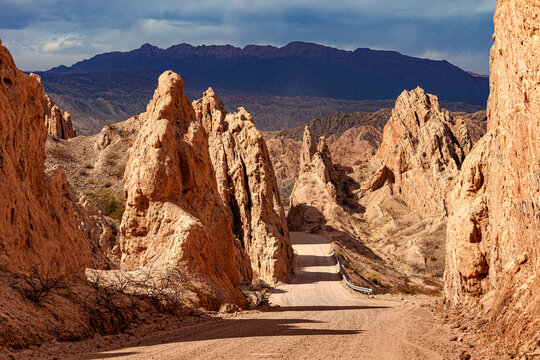 Landscape of contrasts with dirt road and pointed sandstone formations.