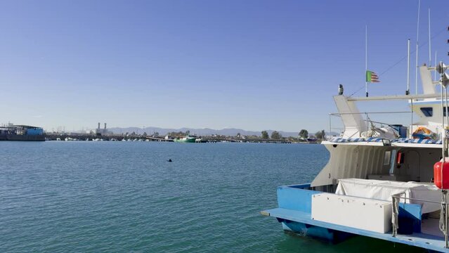 Fishing boats and ships in the port of Castellon in winter. Port cranes on the horizon. Red floats for nets. Port of El Grao. Spain