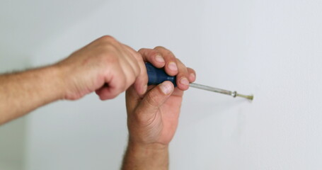 Closeup hand screwing nail on wall