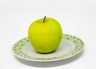 Green apple on a plate with white background.