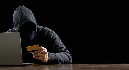 Hacker spy man one person black hoodie sitting hand holding credit card look computer laptop used...