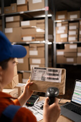 Warehouse worker scanning barcode on parcel using barcode scanner preparing parcels for shipment. - obrazy, fototapety, plakaty