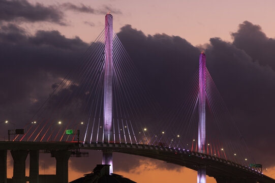 Gerald Desmond Bridge, located in the Port of Long Beach, California, shown at dusk against dark, storm clouds.