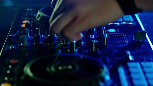 DJ's Hands Adjusting Sound Mixer Under Club Lights