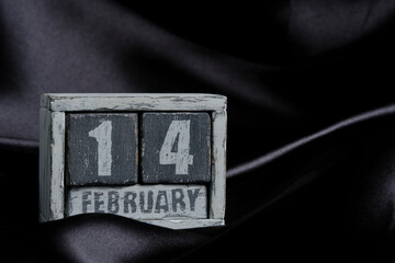 February 14 on wooden calendar on background of black silk fabric, Valentines day.