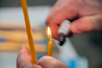 Male hands ignite the fire of a holy church candle