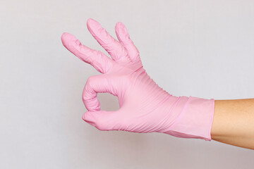 A hand in a medical pink glove shows the sign ok. Approval for surgery