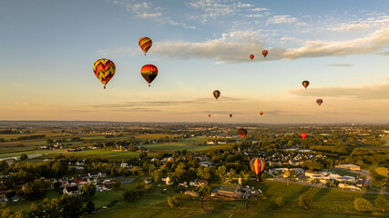 An Aerial View of Multiple Hot Air Balloons Floating Away in Rural Pennsylvania at Sunrise on a Sunny Summer Morning