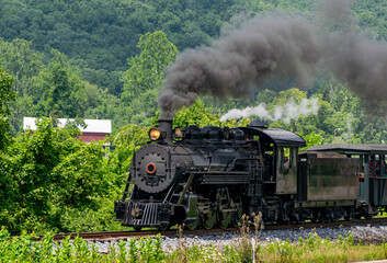 A View of a Narrow Gauge Restored Steam Passenger Train Blowing Smoke, Approaching Travel thru...