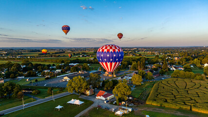 An Aerial View of Multiple Hot Air Balloons Floating Away in Rural Pennsylvania at Sunrise on a...