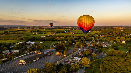 An Aerial View of Two Hot Air Balloons Launching and Floating Away at Sunrise on a Sunny Summer...