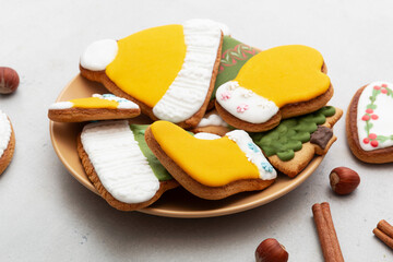 Christmas gingerbread cookies in a plate on a light background. Cinnamon sticks, pine cones and hazelnuts are added for decoration. Top view.