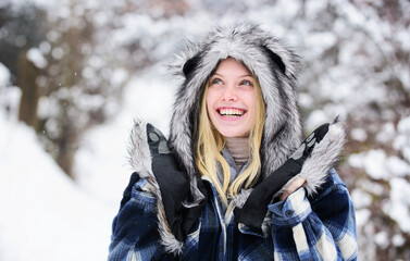 Happy woman enjoying snowy winter day. Christmas girl in plaid coat, fur hat and mittens. Fashion girl in winter season. Beautiful woman in warm clothing in winter park. Winter holidays and vacation.