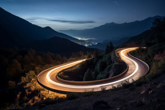 Aerial panoramic view of curvy mountain road with trailing lights at night. Winding road with car speed lights. Beautiful countryside landscape
