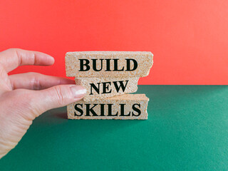 Build new skills symbol. Concept word Build new skills on beautiful brick blocks. Beautiful red background, green table. Businessman hand. Business, education build new skills concept.