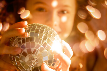 girl holding a disco ball and laughing, play of light, glare and reflection. The concept dreams, makes and wishes come true