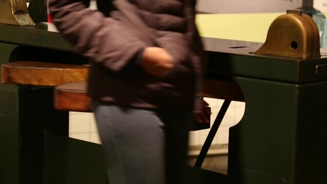 woman walks through subway turnstyle (retro metal and wood metro entrance) nyc train fare (paying customer riding train)