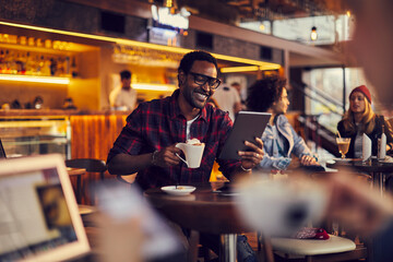 Smiling young man using tablet in cafe