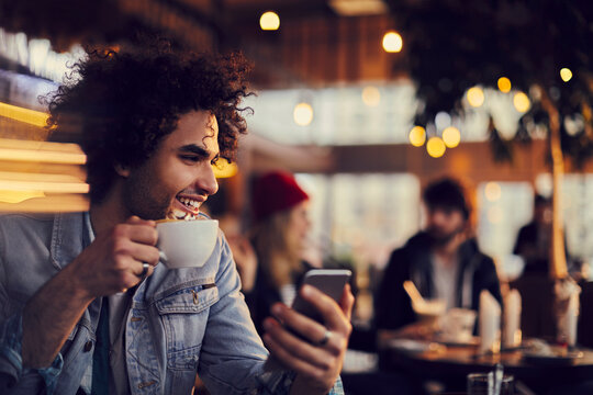 Smiling Young Man Using Smartphone In Cafe