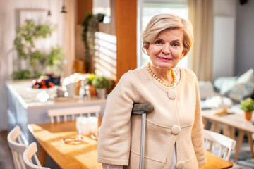 Elegant Senior Woman with Cane Standing in a Bright Home Interior